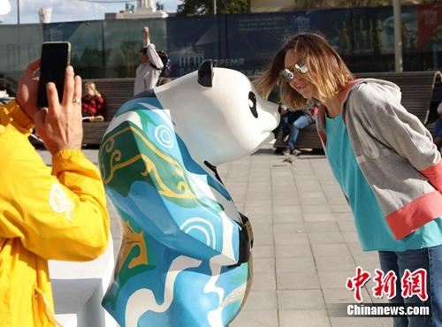 当地时间9月14日，一名俄罗斯民众正与彩绘大熊猫合影。当天莫斯科“中国节”文化活动在全俄展览中心举行。 王修君 摄