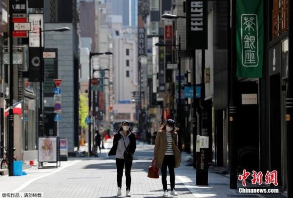 当地时间4月25日，日本东京，戴口罩的女士走过空无一人的购物区。