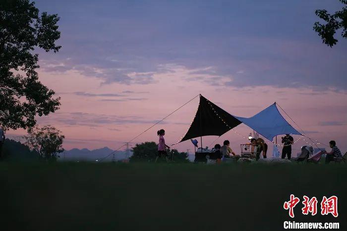 资料图：2022年7月23日，民众在重庆广阳岛一处露营地搭起帐篷，享受夏日傍晚的惬意。<a target='_blank' href='/'>中新社</a>记者 何蓬磊 摄